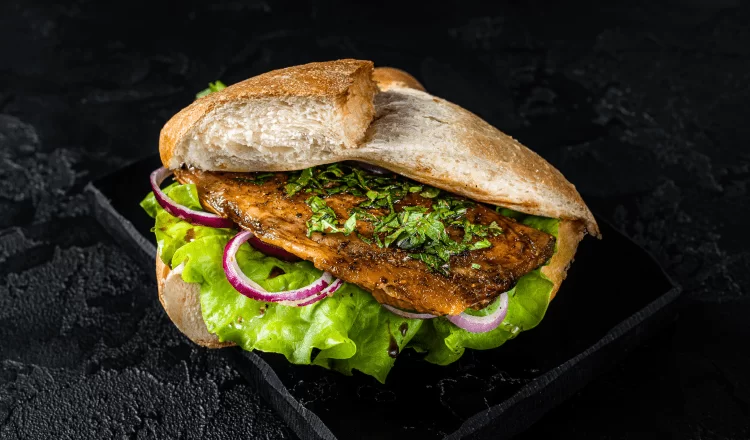 Half portion of fish and bread sandwich with various ingredients