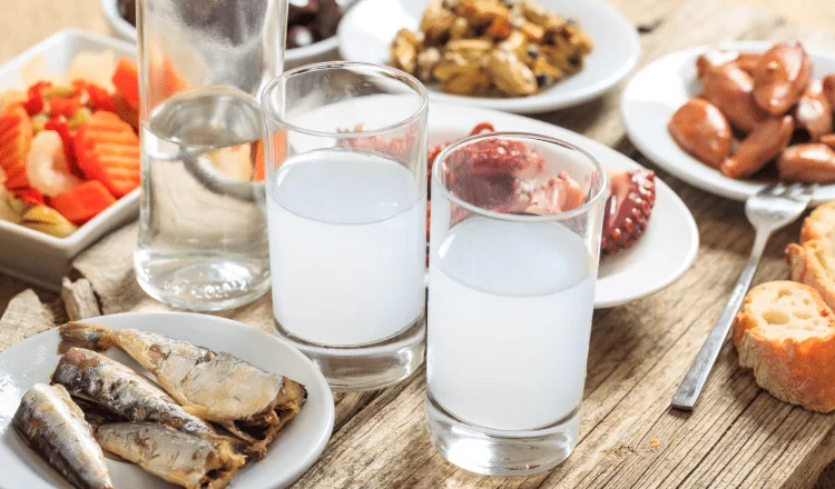 Two raki glasses standing with appetizers on the tavern table
