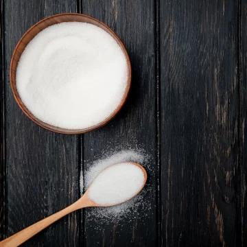 A bowl of sugar and a spoon of sugar standing on the table